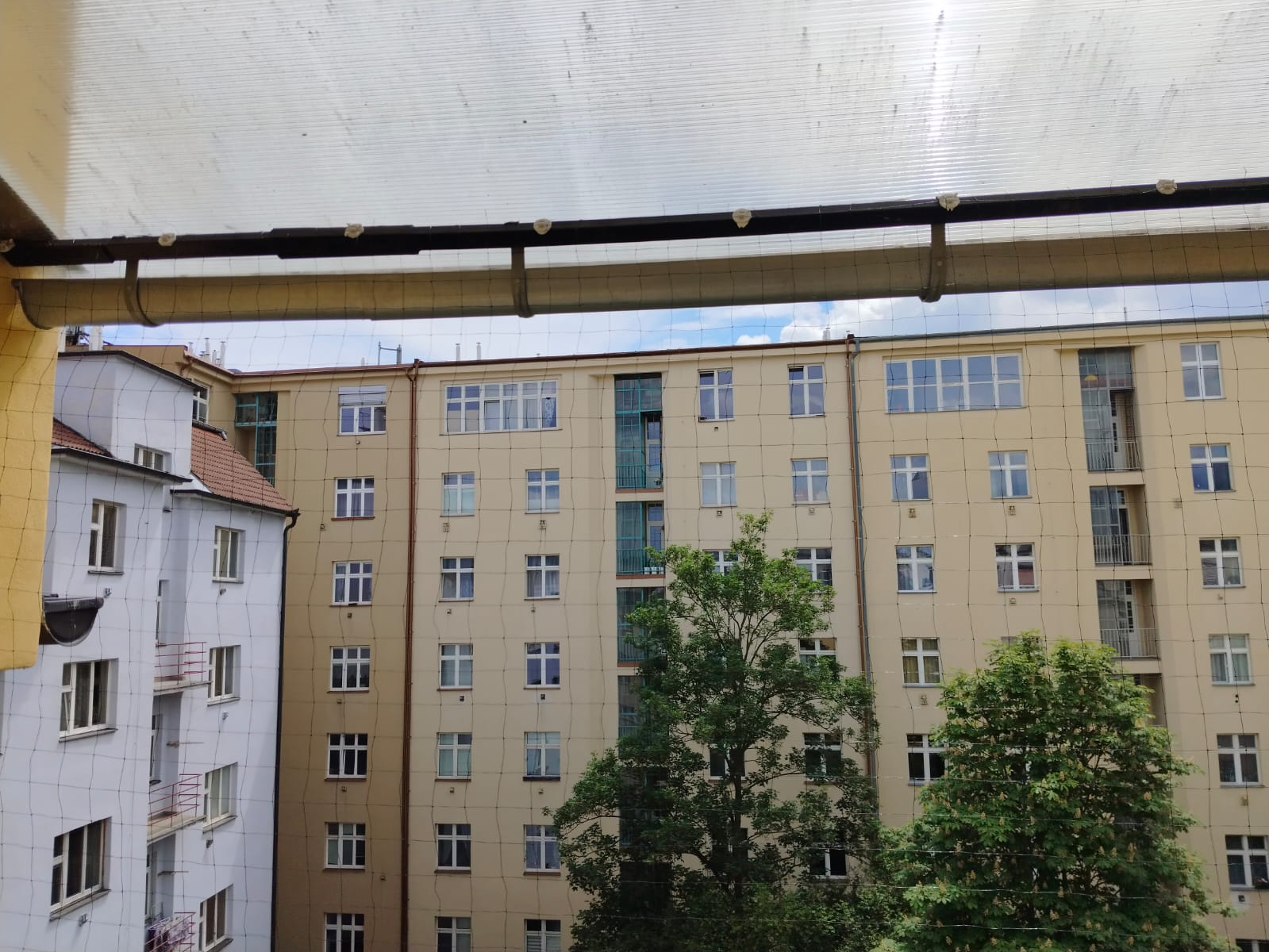 Ochranná síť proti holubům instalovaná na bytovém domě v Kladně