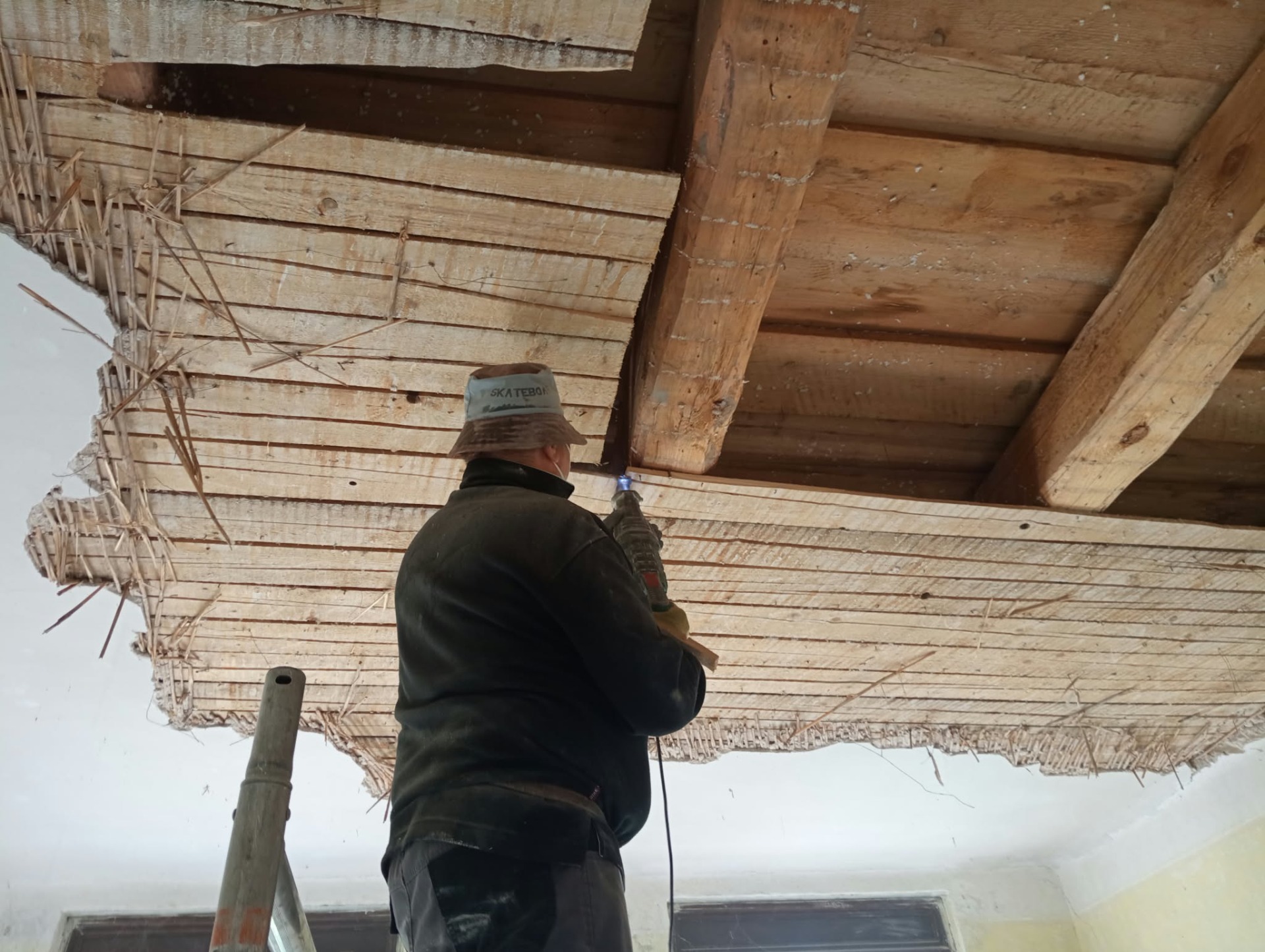 Bourací práce při odstraňování stropních vrstev a odkrývání dřevěné konstrukce v interiéru domu